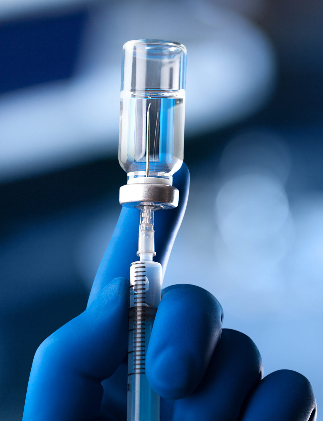 A medical hand in a glove holds an ampoule with a vaccine and a syringe with illustration
